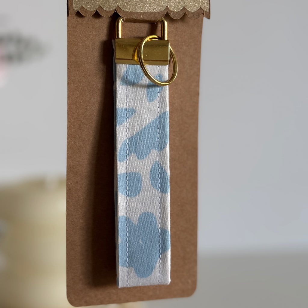 Porte Clé Lyra – Motif fleurs bleu ciel avec finitions dorées