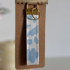 Porte Clé Léna – Motif fleurs bleu ciel avec finitions dorées
